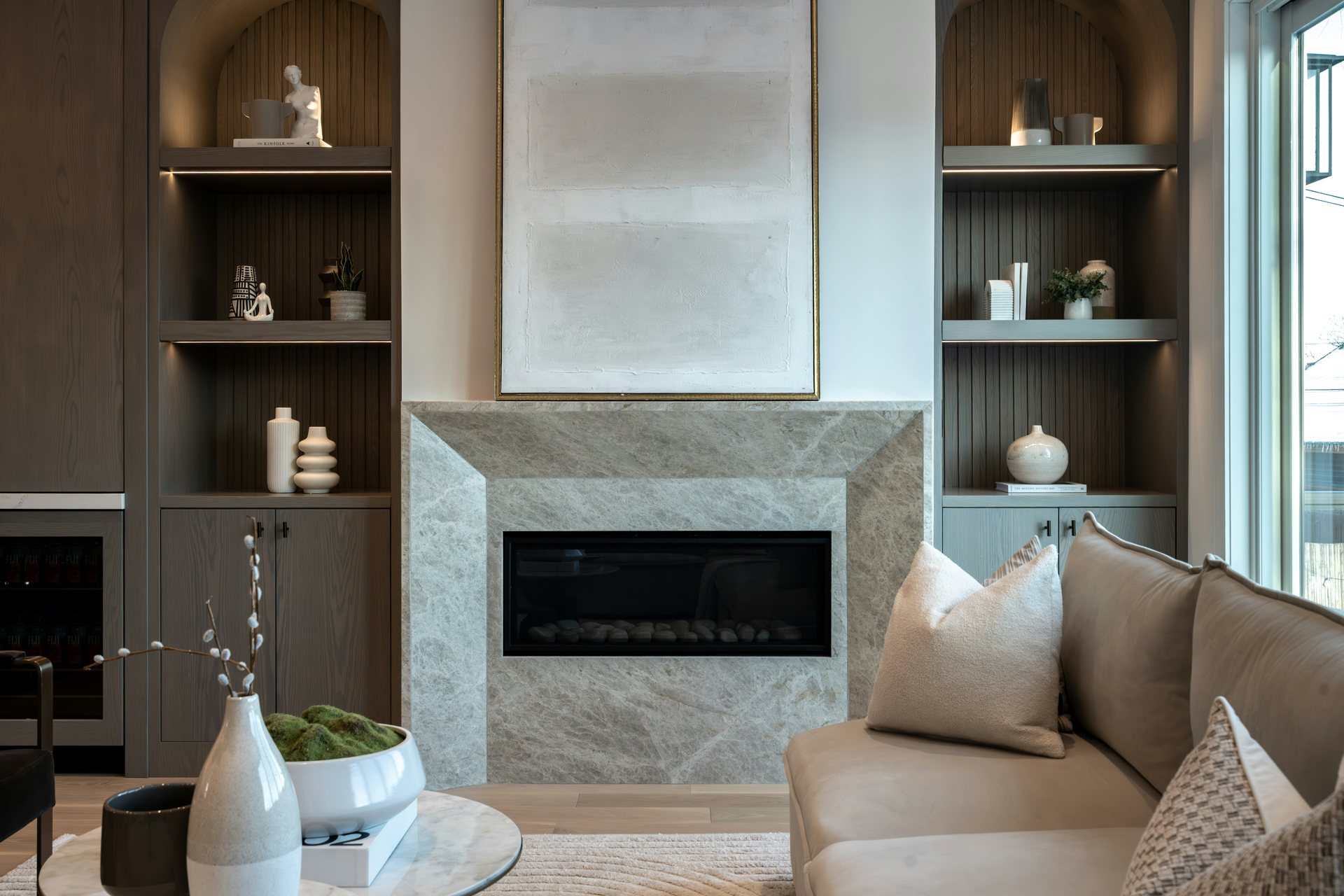 Modern living room with a centered stone fireplace, arched wood shelves and a light sofa